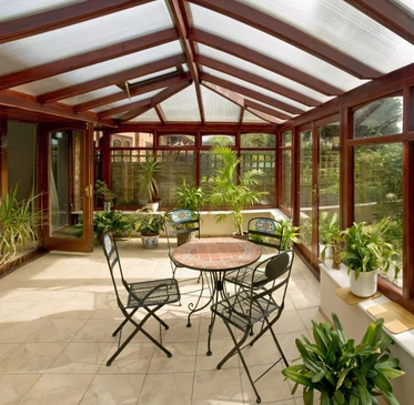 Véranda résidentielle avec structure en bois et verrière, aménagée en salon de jardin