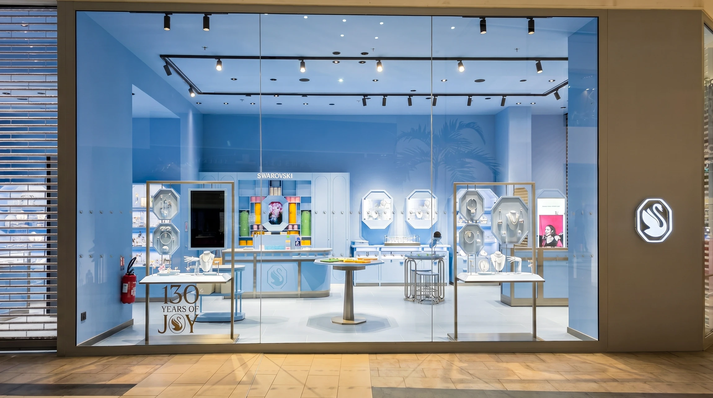 Façade vitrée d'une boutique Swarovski en centre commercial, célébrant ses 130 ans