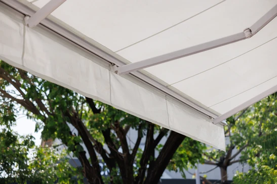 Ext&eacute;rieur r&eacute;sidentiel avec store banne r&eacute;tractable d&eacute;ploy&eacute; au-dessus d'une terrasse