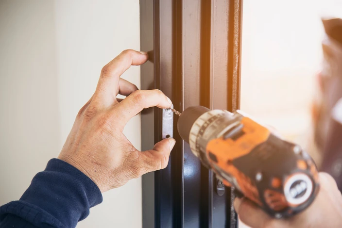 Homme faisant du cadre d'aluminium avec lunettes et filetage et installation de portes et de fenêtres sur le chantier