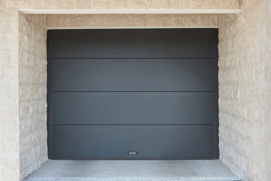 Fa&ccedil;ade ext&eacute;rieure r&eacute;sidentielle moderne avec porte de garage sectionnelle grise &agrave; fen&ecirc;tres rectangulares